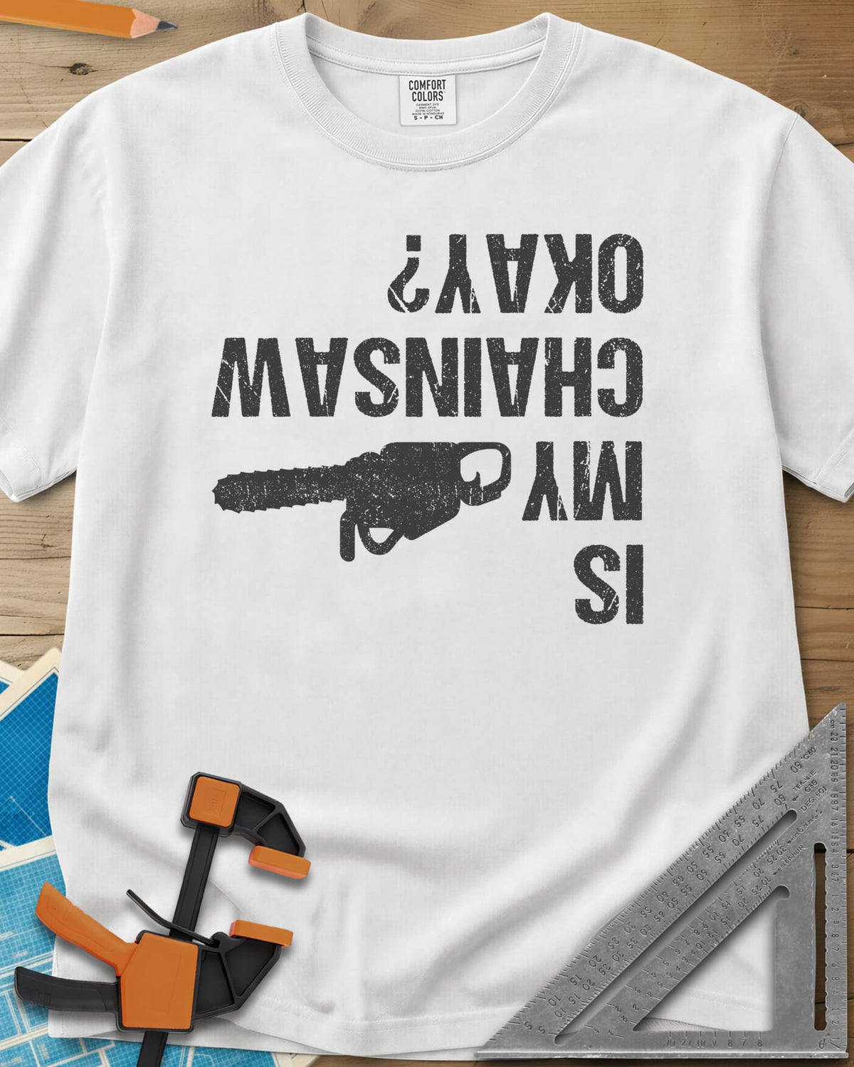 Chainsaw Okay? heavyweight tee in White, upside-down distressed lettering beside a chainsaw on its side