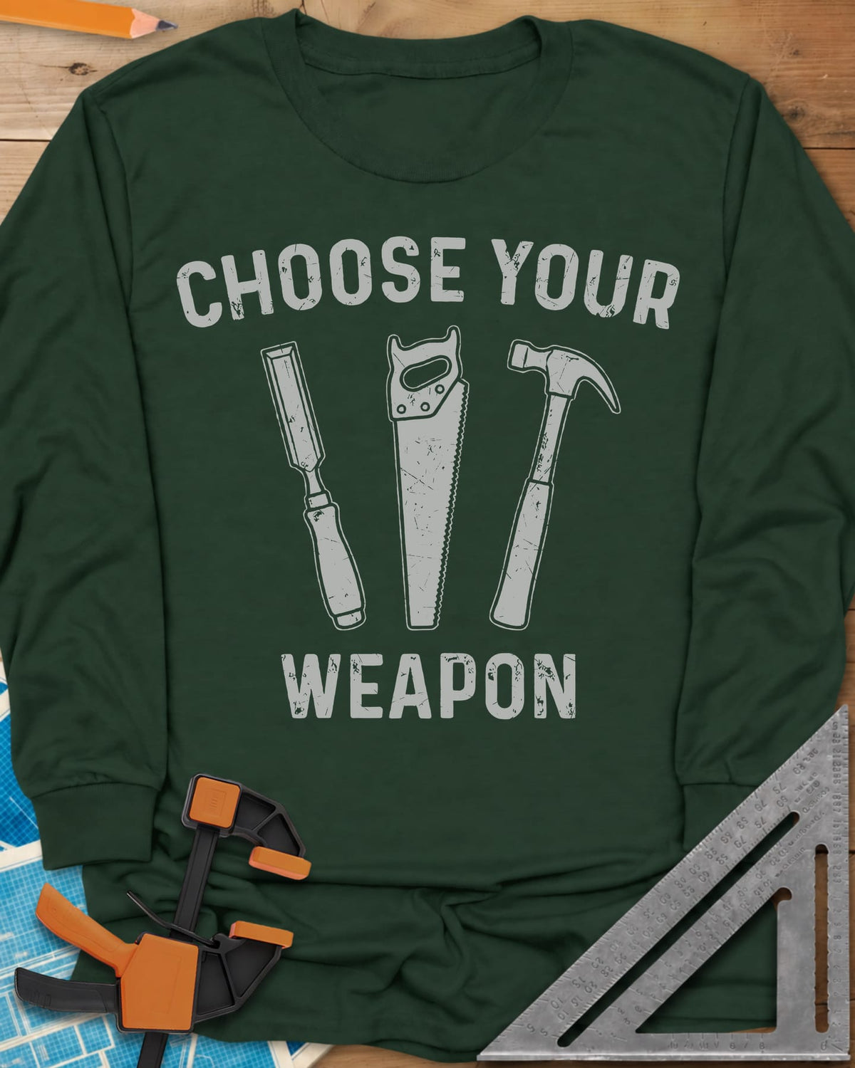Choose Your Weapon long sleeve shirt in Forest Green, a chisel, a handsaw and a claw hammer standing in a row