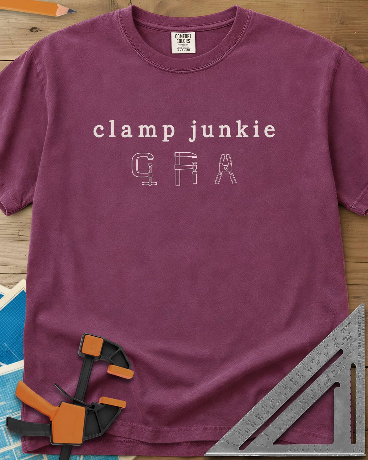 Clamp Junkie heavyweight tee in Berry, outline drawings of a C-clamp, a bar clamp and a spring clamp