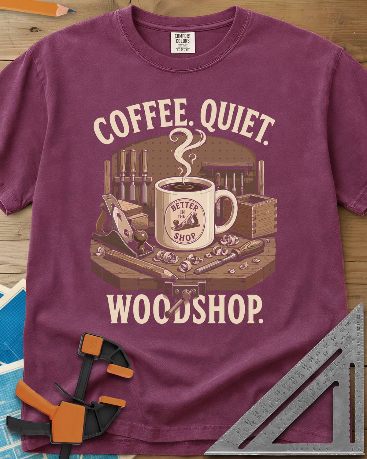 Coffee. Quiet. Woodshop. heavyweight tee in Berry, steaming mug on a workbench with chisels, a plane and wood curls