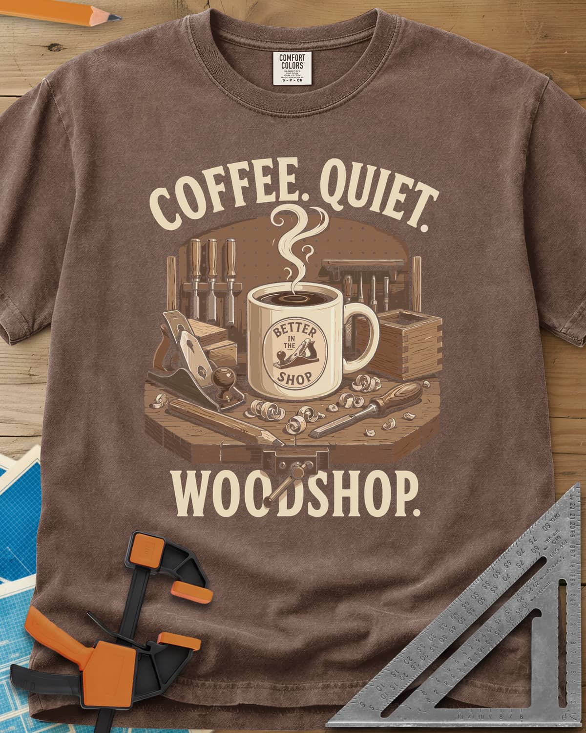 Coffee. Quiet. Woodshop. heavyweight tee in Espresso, steaming mug on a workbench with chisels, a plane and wood curls