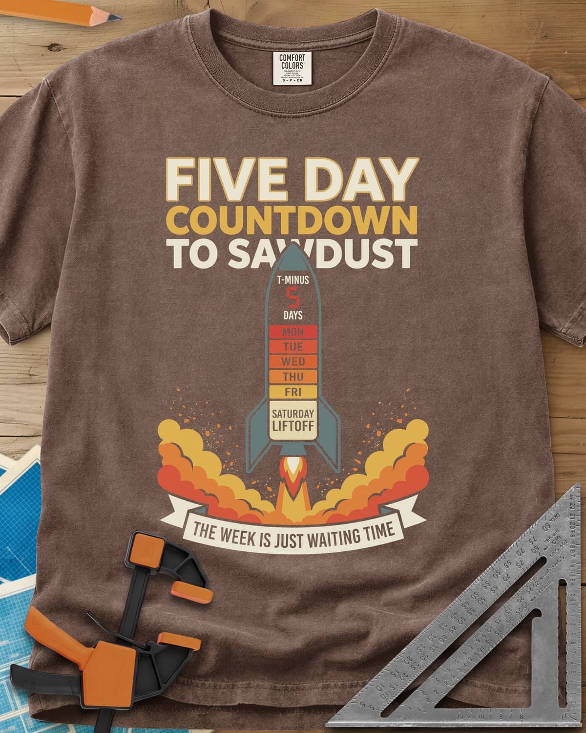 Countdown to Sawdust heavyweight tee in Espresso, a rocket with a Monday-to-Saturday countdown on its hull