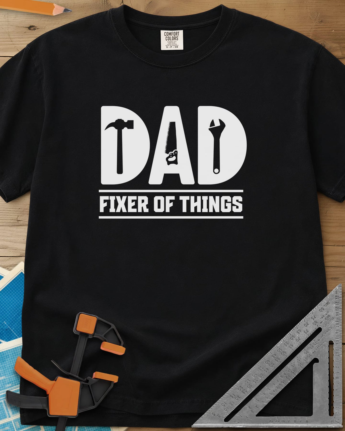 Dad, Fixer of All Things heavyweight tee in Black, big letters spelling DAD with a hammer, saw and wrench cut in