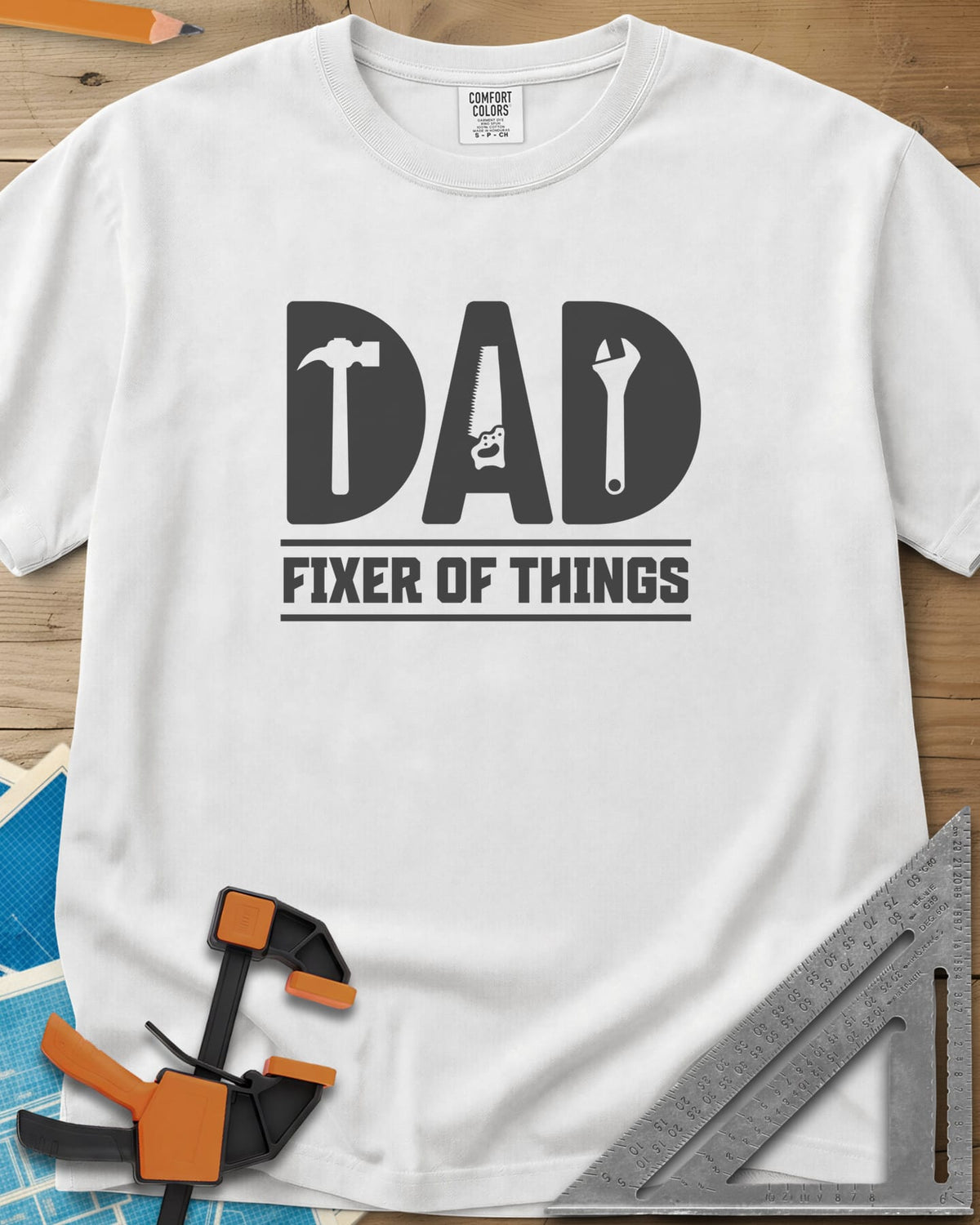 Dad, Fixer of All Things heavyweight tee in White, big letters spelling DAD with a hammer, saw and wrench cut in