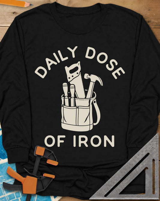 Daily Dose long sleeve shirt in Black, a canvas tool bag holding a handsaw, hammer and two chisels
