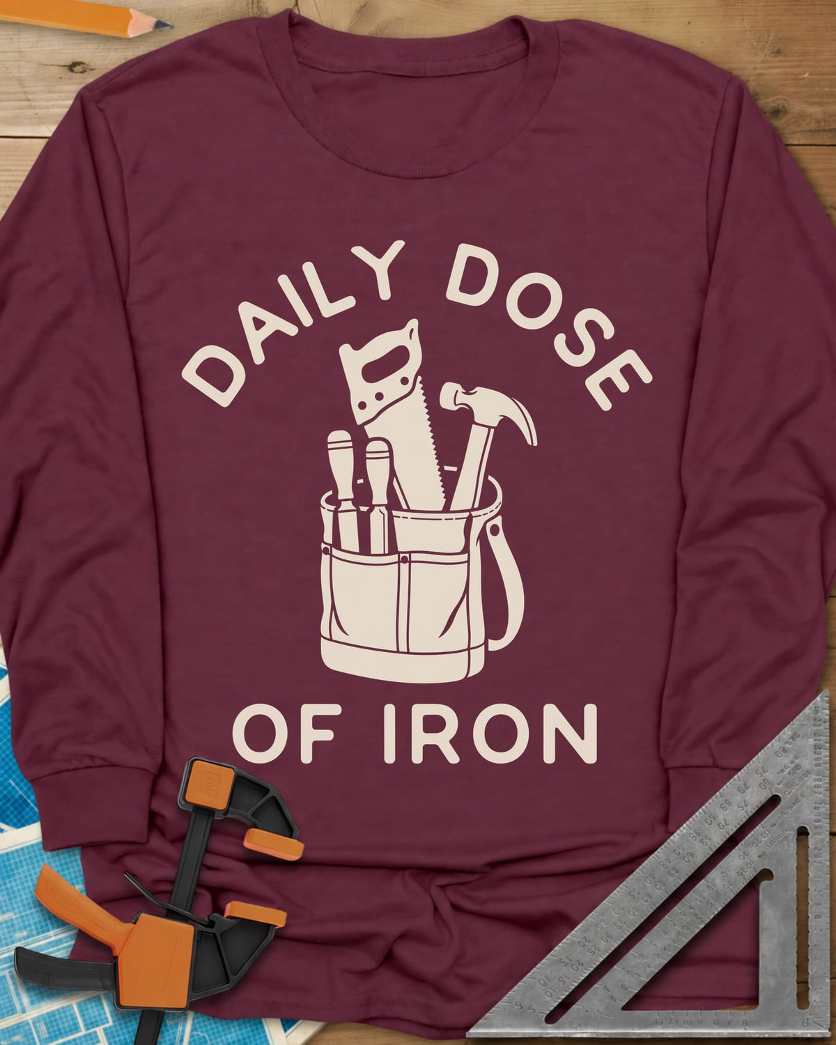 Daily Dose long sleeve shirt in Maroon, a canvas tool bag holding a handsaw, hammer and two chisels