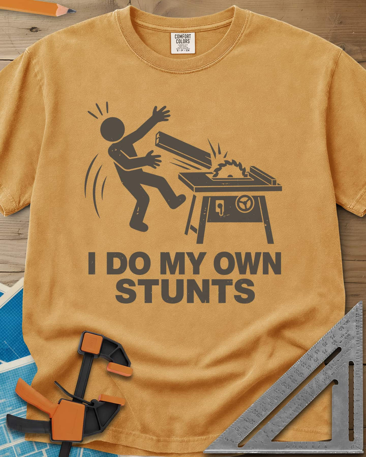 DIY Stunts heavyweight tee in Mustard, a stick figure leaning back as a board flies off a table saw