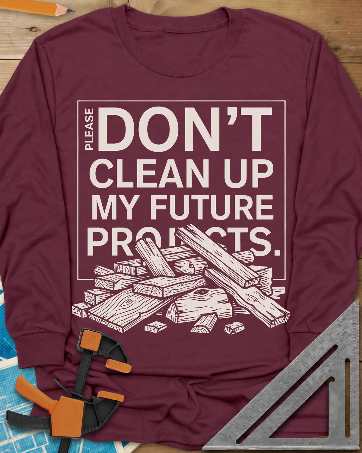 Don't Clean Up My Future Projects long sleeve shirt in Maroon, a boxed plea with a pile of boards and offcuts below