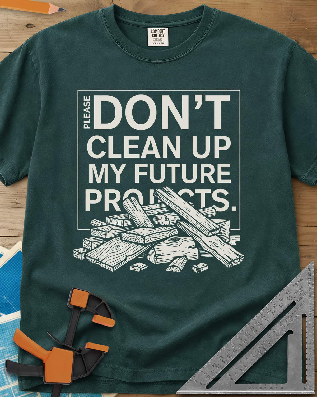 Don't Clean Up My Future Projects heavyweight tee in Blue Spruce, a boxed plea with a pile of boards and offcuts below