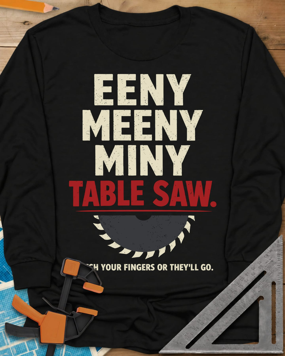 Eeny Meeny Table Saw long sleeve shirt in Black, stacked nursery-rhyme lettering above a half saw blade
