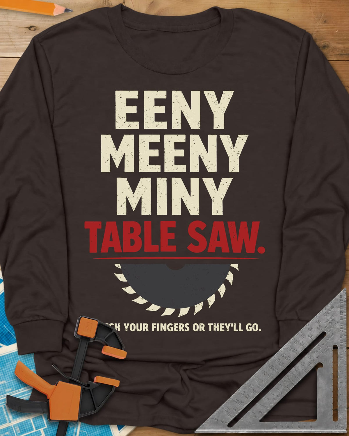 Eeny Meeny Table Saw long sleeve shirt in Dark Chocolate, stacked nursery-rhyme lettering above a half saw blade
