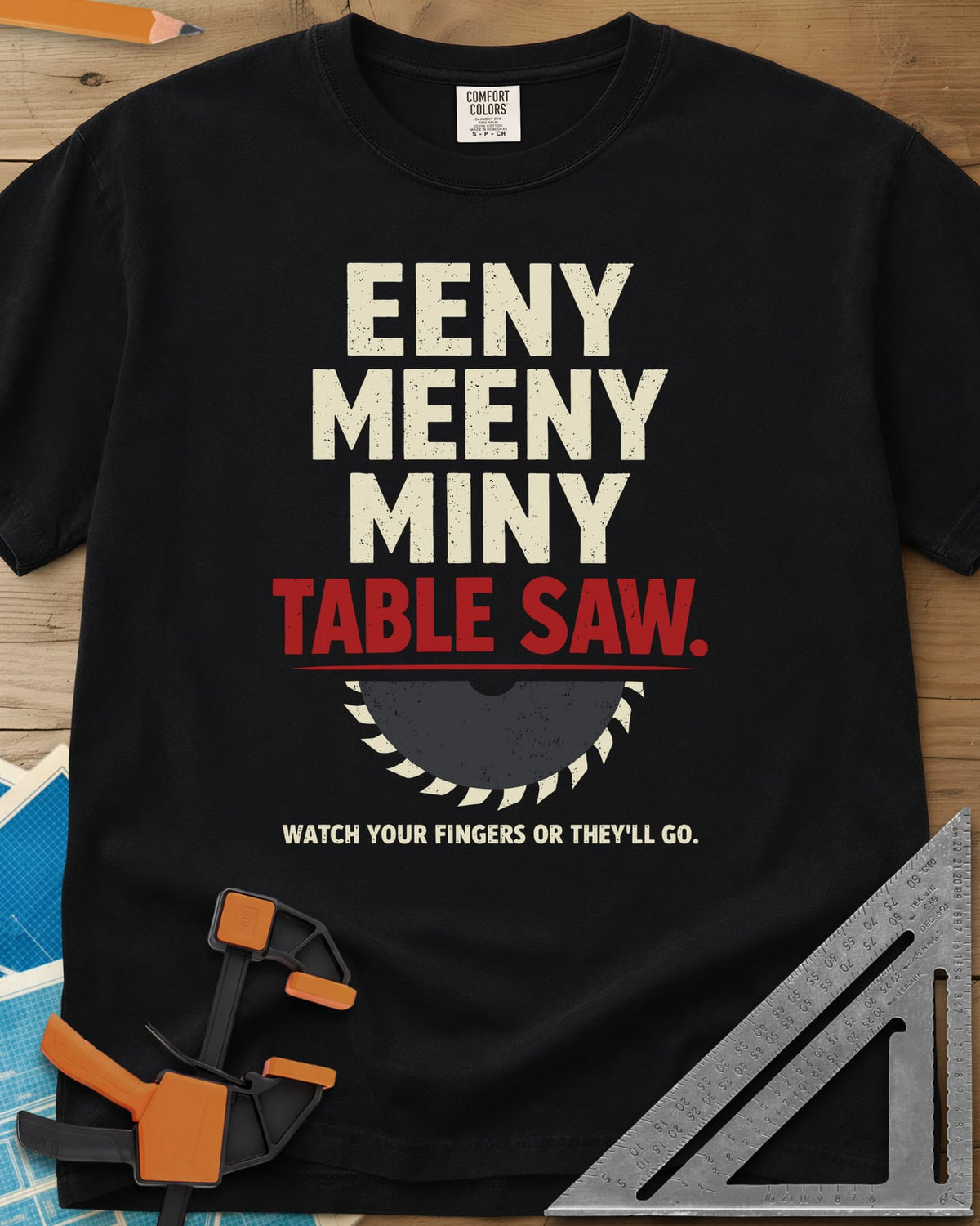 Eeny Meeny Table Saw heavyweight tee in Black, stacked nursery-rhyme lettering above a half saw blade