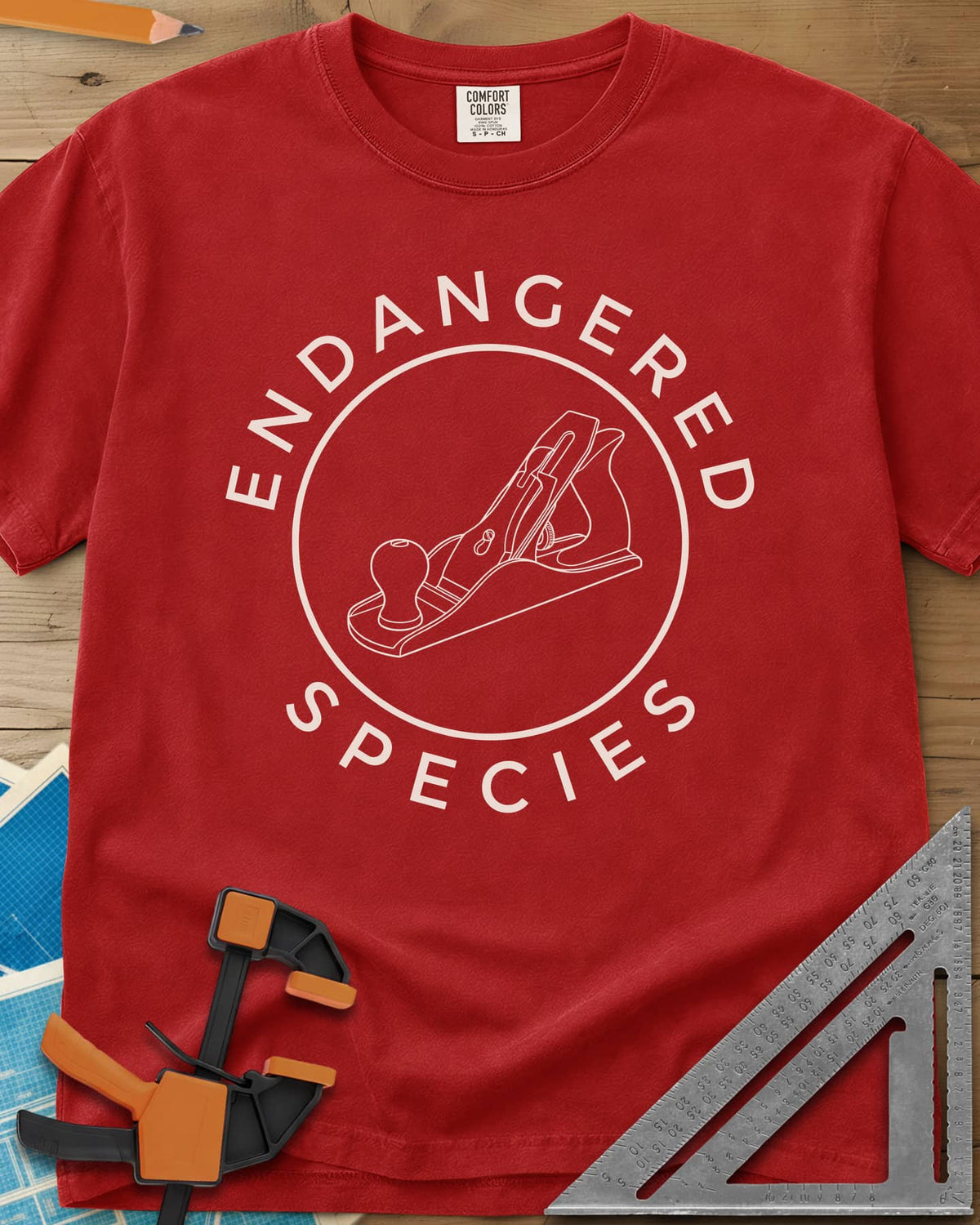 Endangered Species heavyweight tee in Red, a hand plane line drawing inside a rust-red circle
