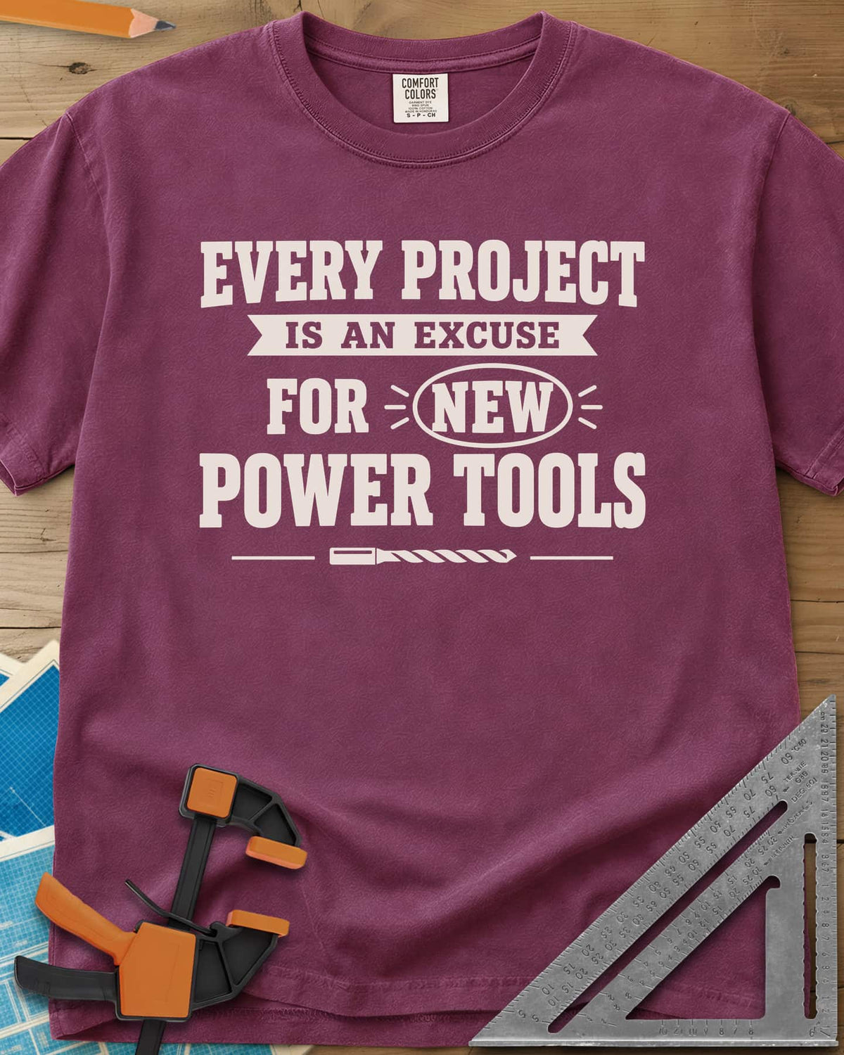Every Project Is An Excuse heavyweight tee in Berry, slogan with a ribbon banner, circled NEW and a drill bit