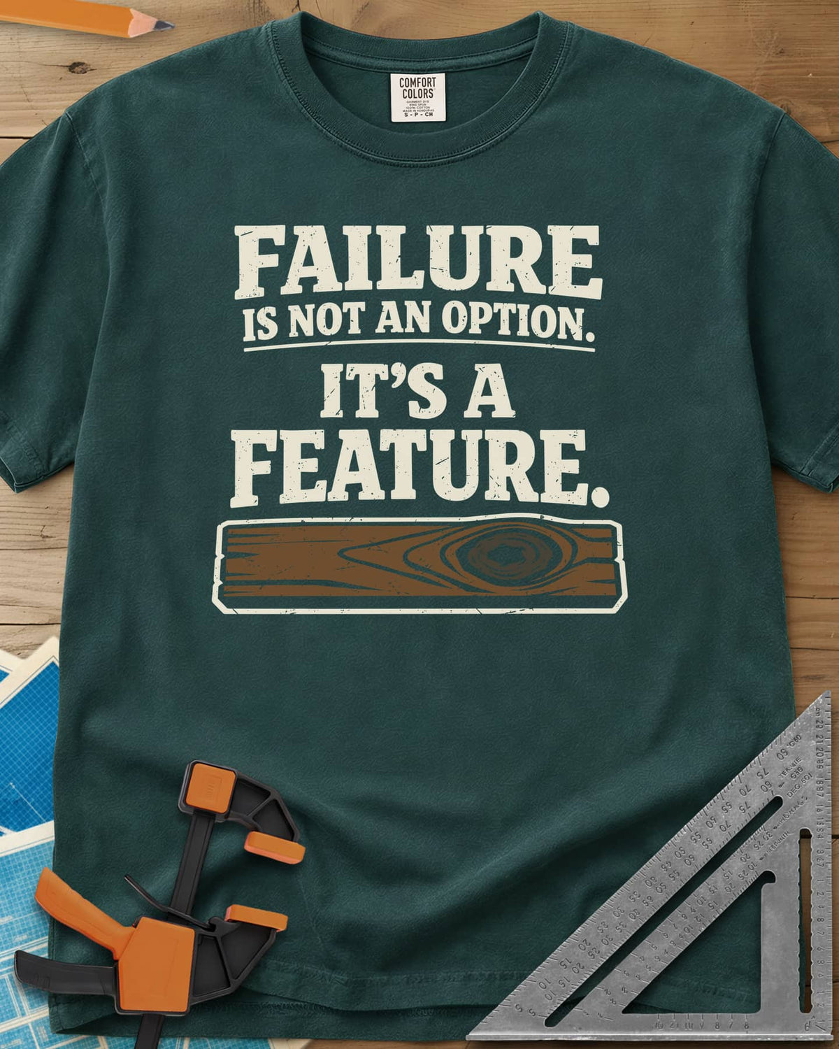 Failure Is A Feature heavyweight tee in Blue Spruce, a knotty plank with a swirling knot under the slogan