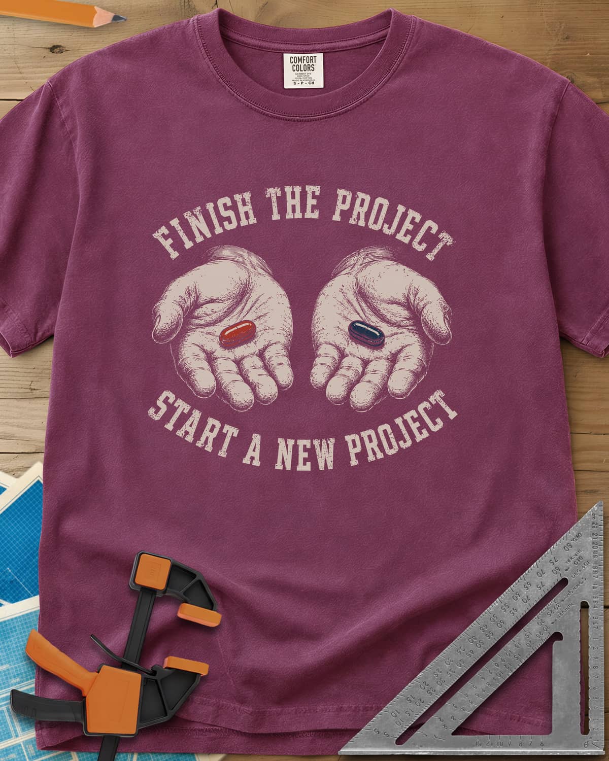 Finish The Project heavyweight tee in Berry, two open hands holding a red pill and a dark blue pill