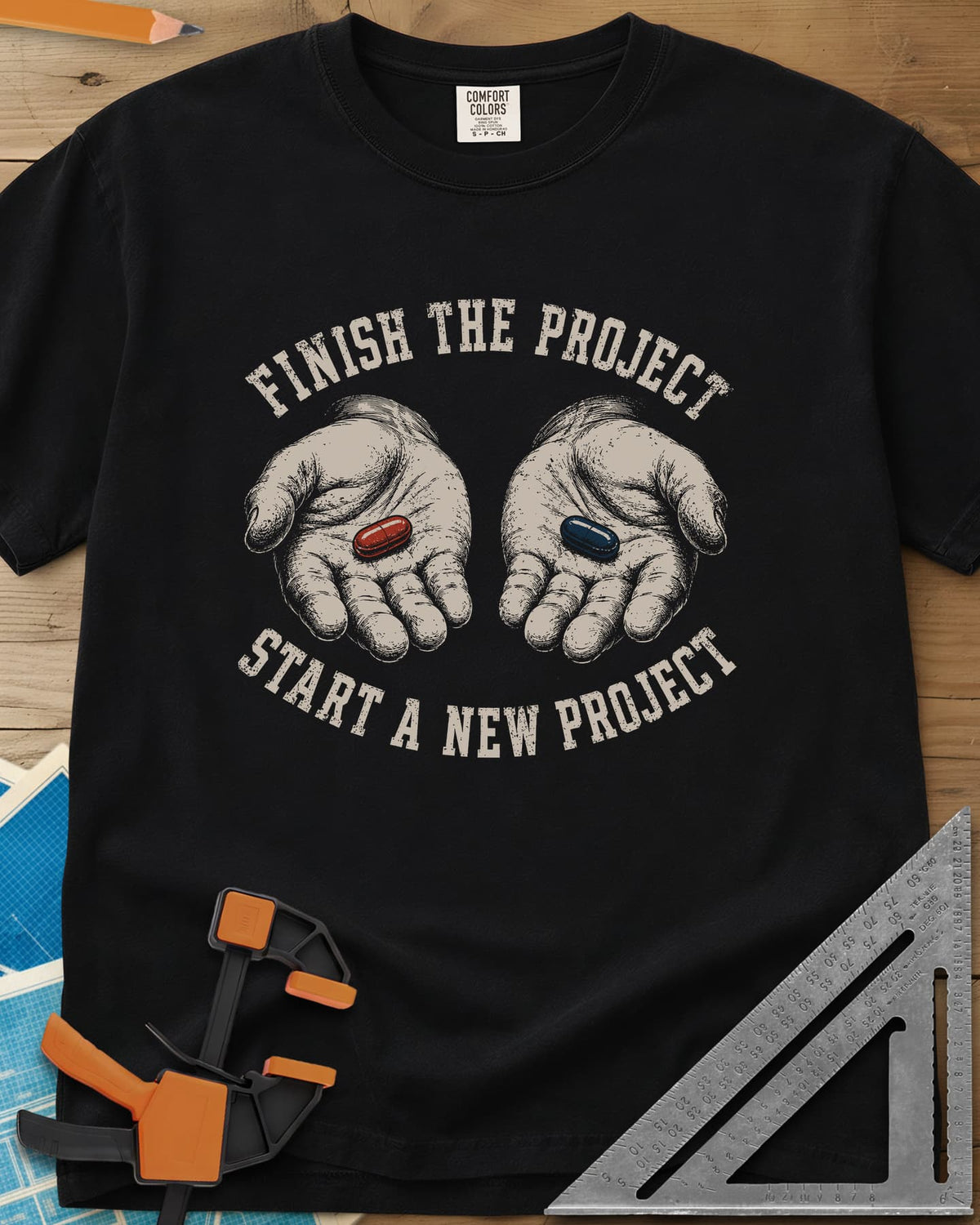 Finish The Project heavyweight tee in Black, two open hands holding a red pill and a dark blue pill