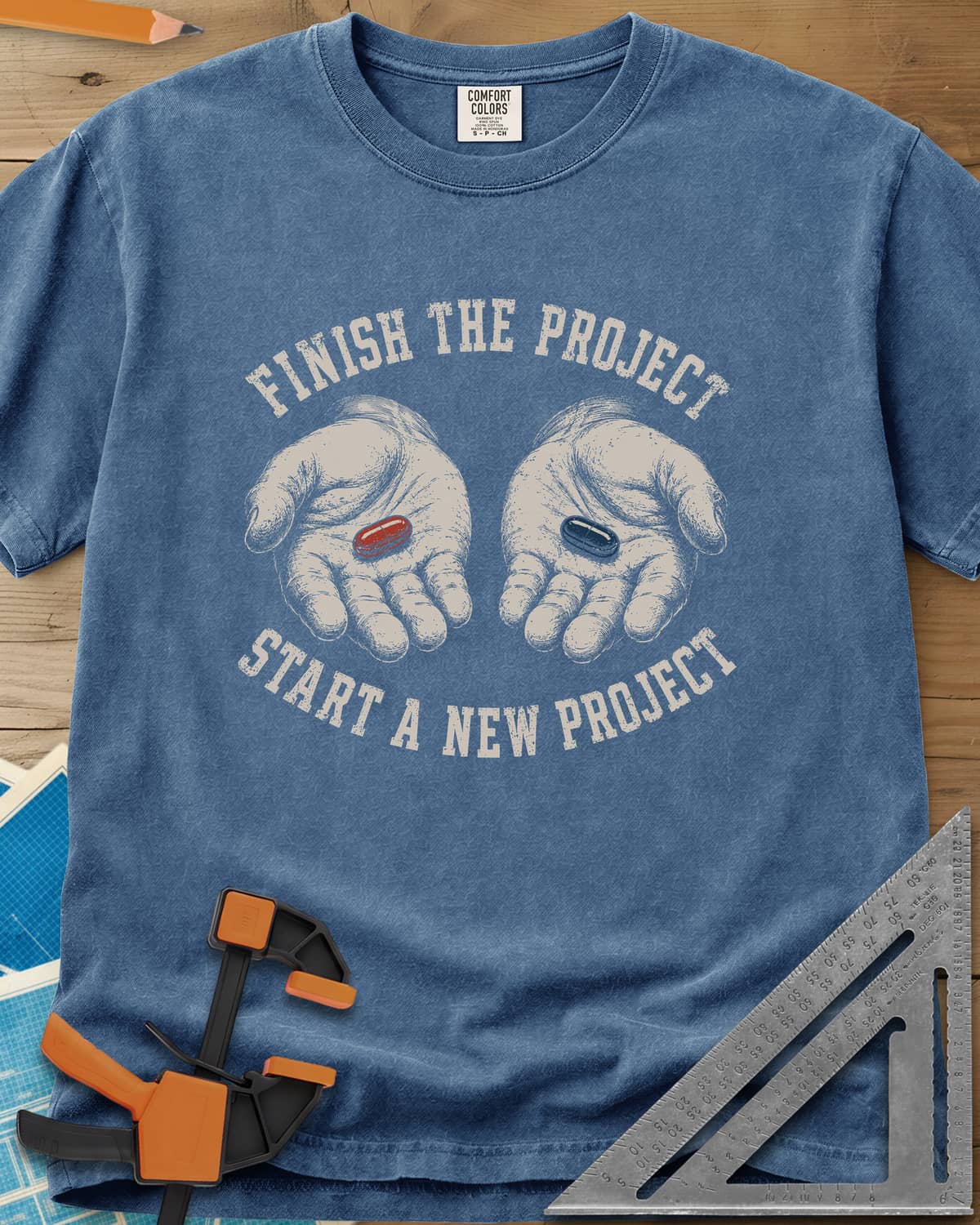 Finish The Project heavyweight tee in Blue Jean, two open hands holding a red pill and a dark blue pill