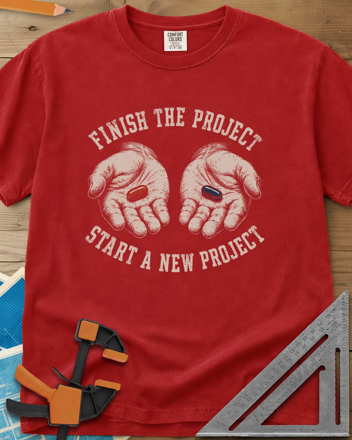 Finish The Project heavyweight tee in Red, two open hands holding a red pill and a dark blue pill