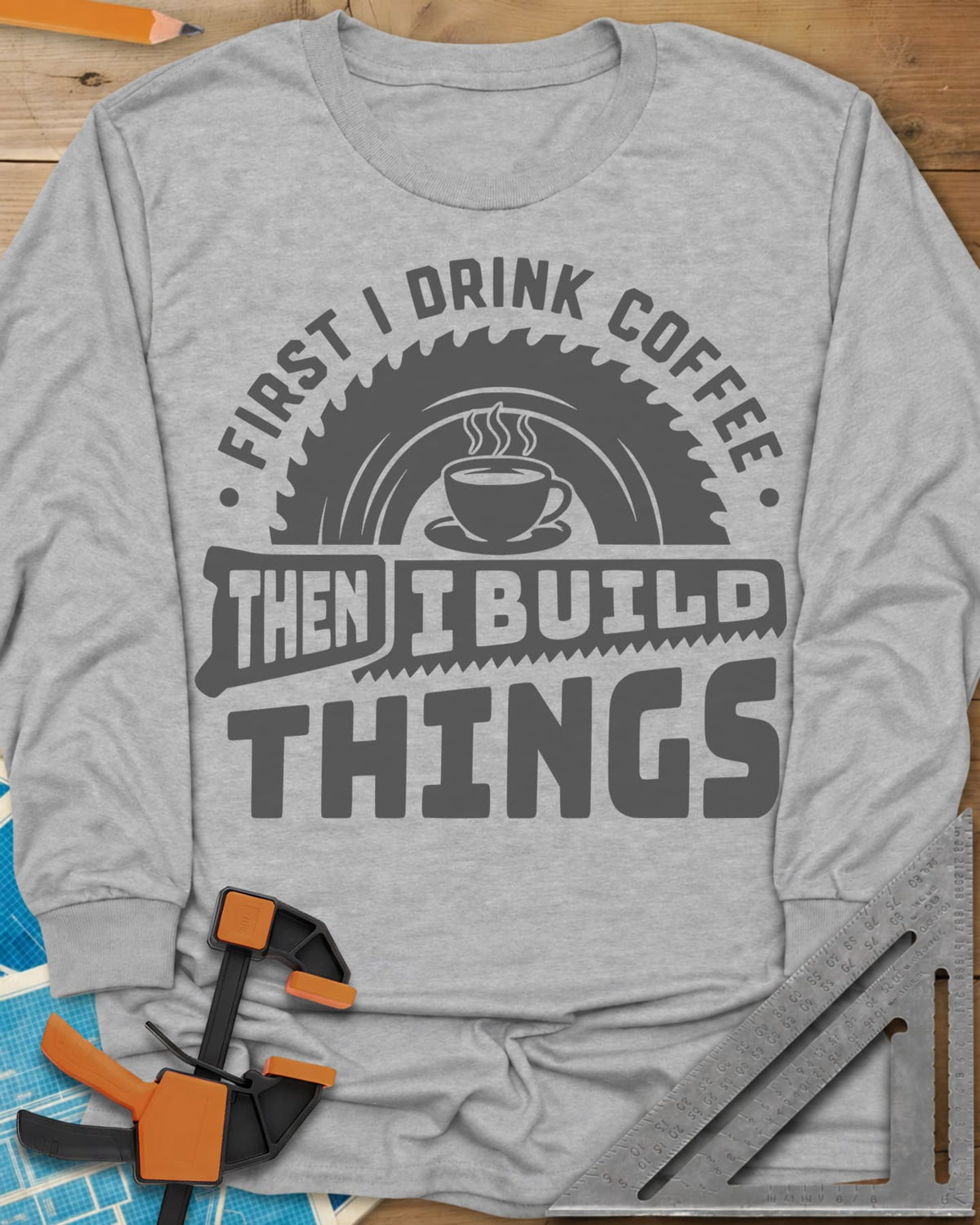 First I Drink Coffee Then I Build Things long sleeve shirt in Sport Grey, a steaming cup before a saw blade, with a handsaw