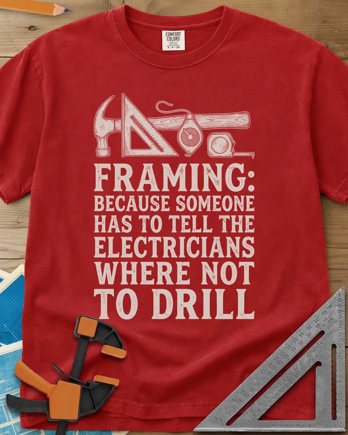 Framing heavyweight tee in Red, a hammer, speed square, chalk line reel and tape measure in a row