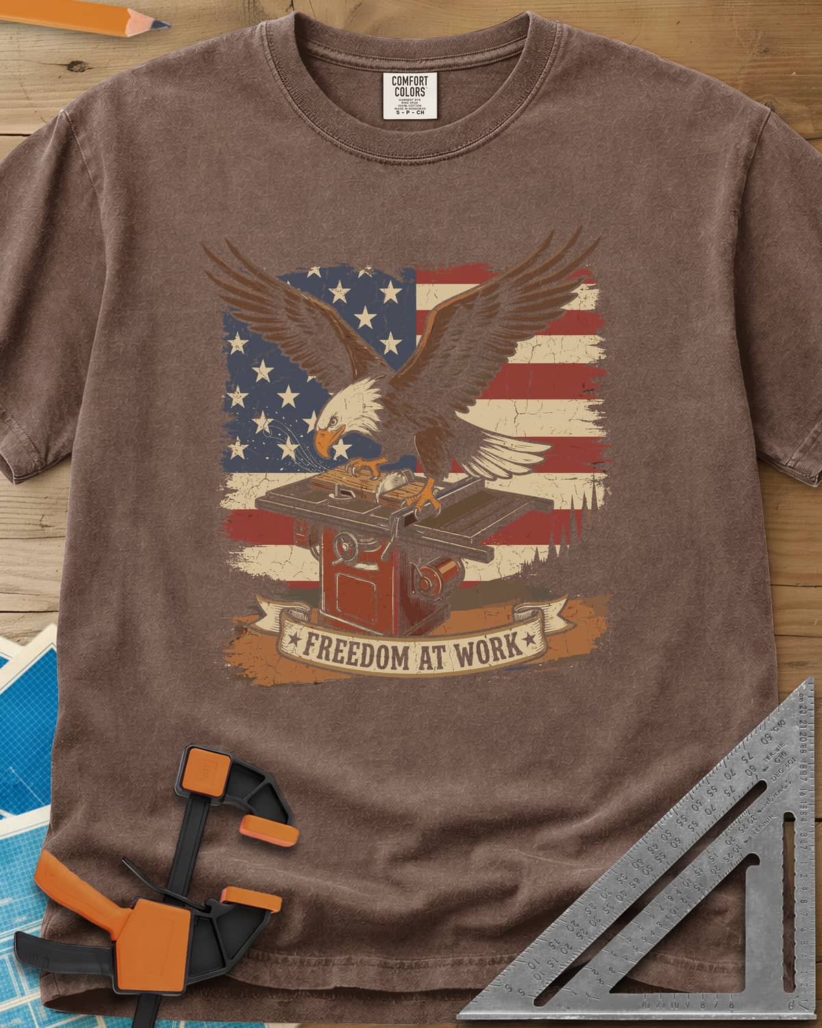 Freedom At Work Woodworking Eagle heavyweight tee in Espresso, a bald eagle on a table saw in front of an American flag