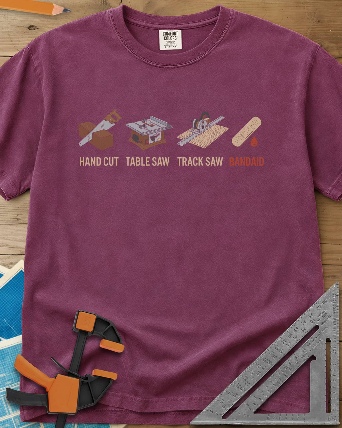 From Handsaw to Bandaid heavyweight tee in Berry, a handsaw, a table saw, a track saw and a bandage with a drop