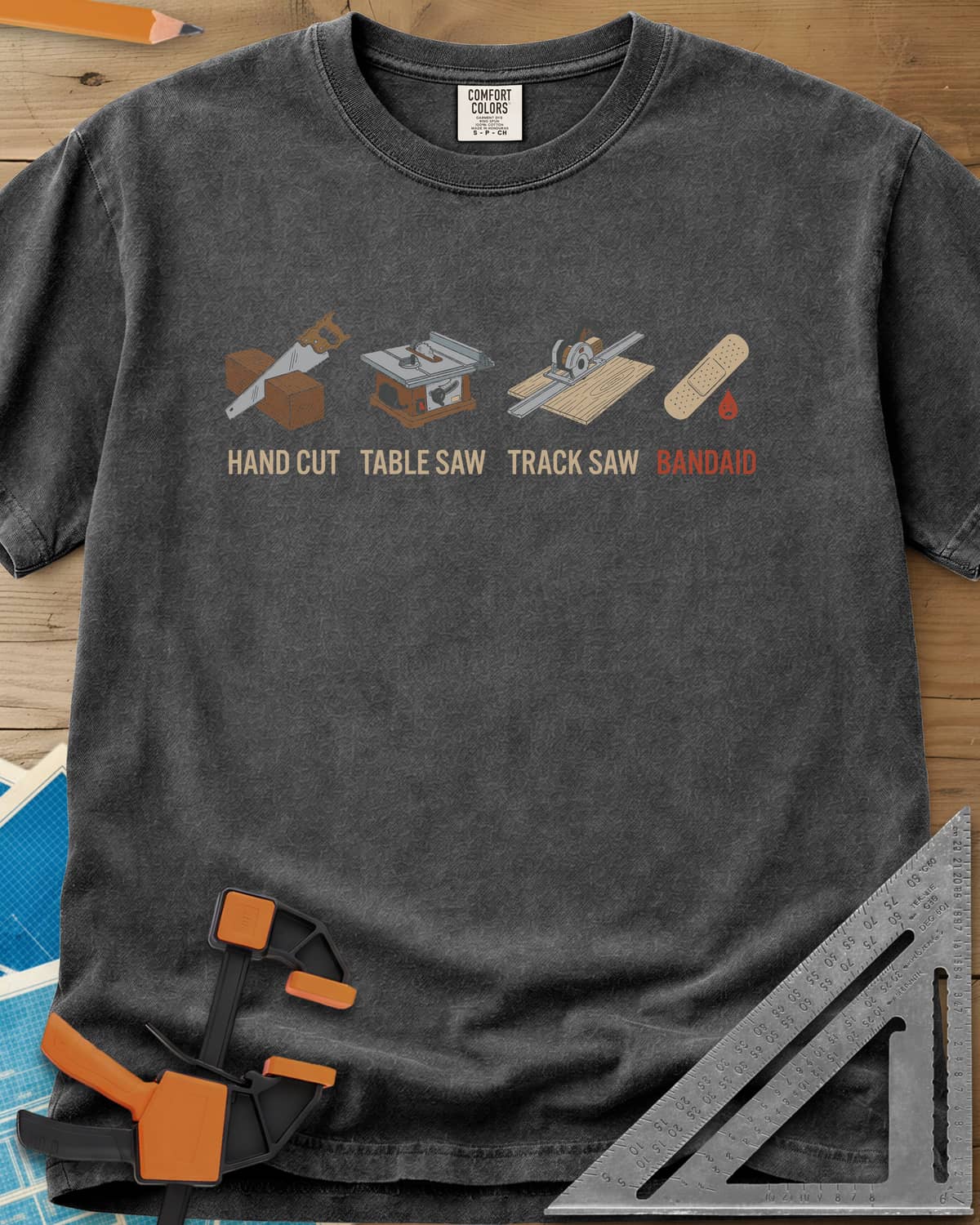 From Handsaw to Bandaid heavyweight tee in Pepper, a handsaw, a table saw, a track saw and a bandage with a drop