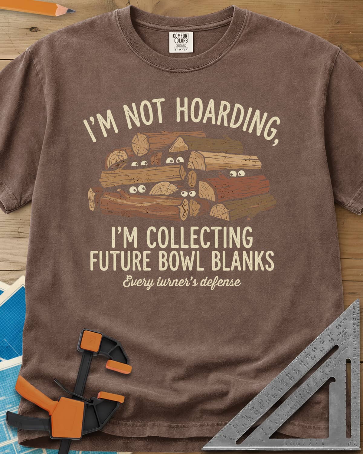 Future Bowl Blanks heavyweight tee in Espresso, a stack of logs with small eyes peeking out from between them