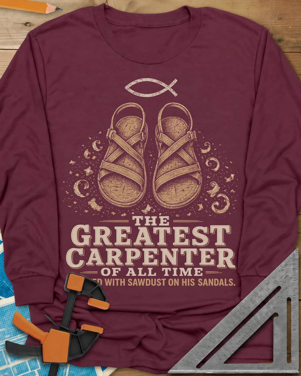 Greatest Carpenter long sleeve shirt in Maroon, fish symbol over sandals dusted with wood shavings