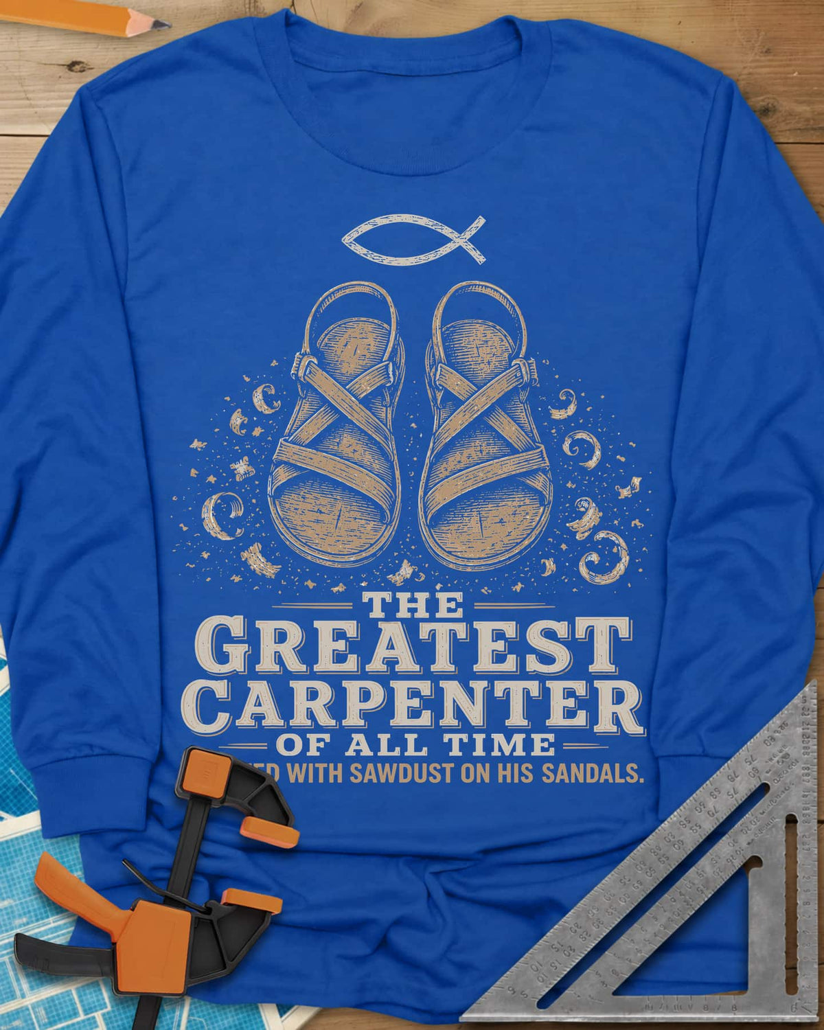 Greatest Carpenter long sleeve shirt in Royal, fish symbol over sandals dusted with wood shavings