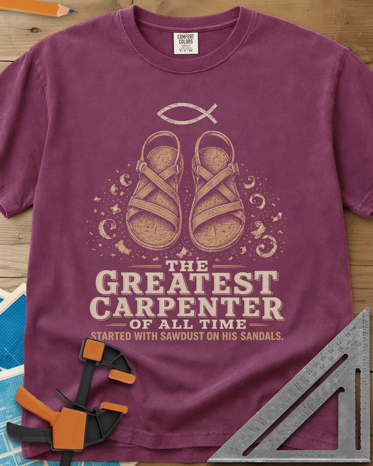 Greatest Carpenter heavyweight tee in Berry, fish symbol over sandals dusted with wood shavings