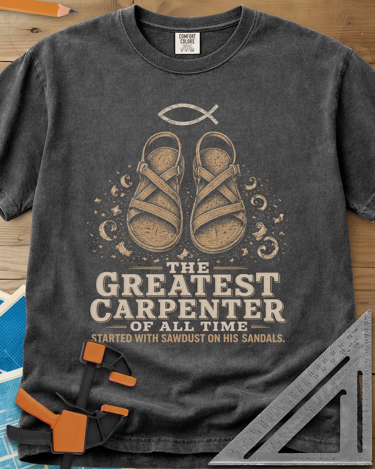 Greatest Carpenter heavyweight tee in Pepper, fish symbol over sandals dusted with wood shavings