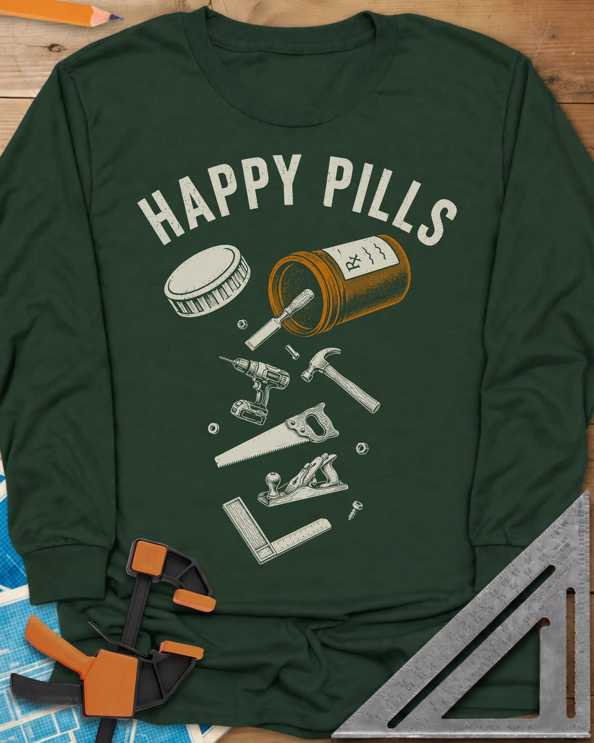 Happy Pills long sleeve shirt in Forest Green, a tipped pill bottle spilling hand tools and a cordless drill
