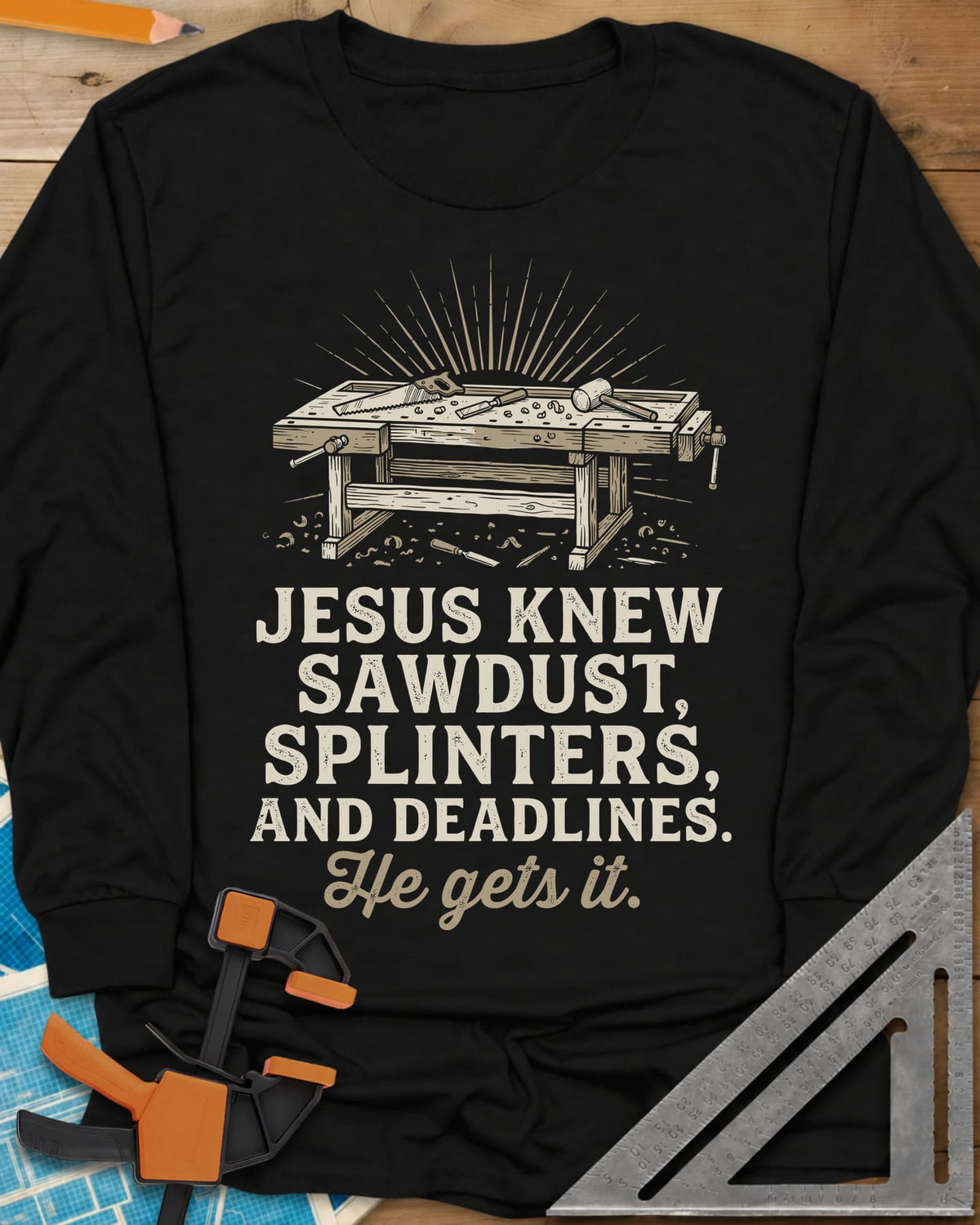 He Gets It Carpenter long sleeve shirt in Black, a workbench under a sunburst with a hand saw, chisel and mallet