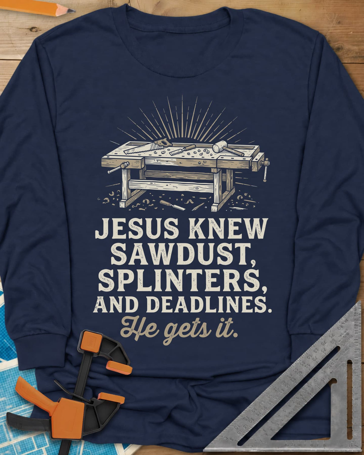 He Gets It Carpenter long sleeve shirt in Navy, a workbench under a sunburst with a hand saw, chisel and mallet