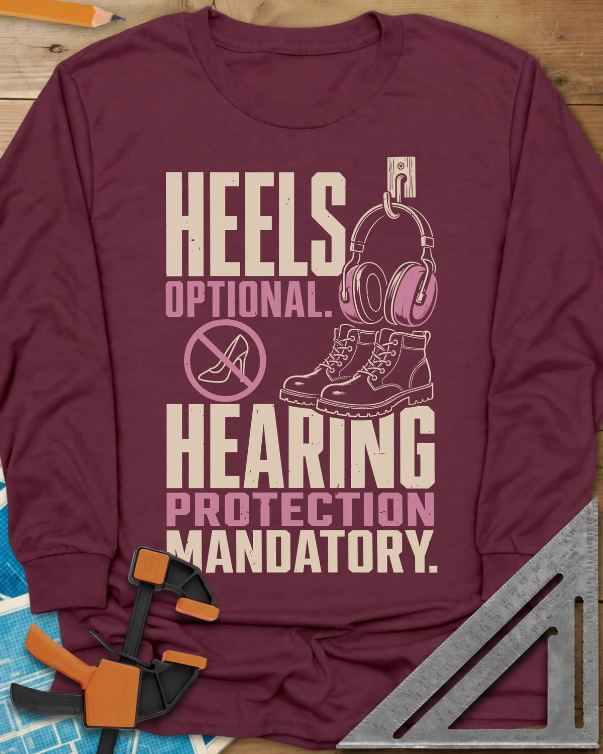 Hearing Protection long sleeve shirt in Maroon, ear muffs on a hook, work boots and a crossed-out high heel
