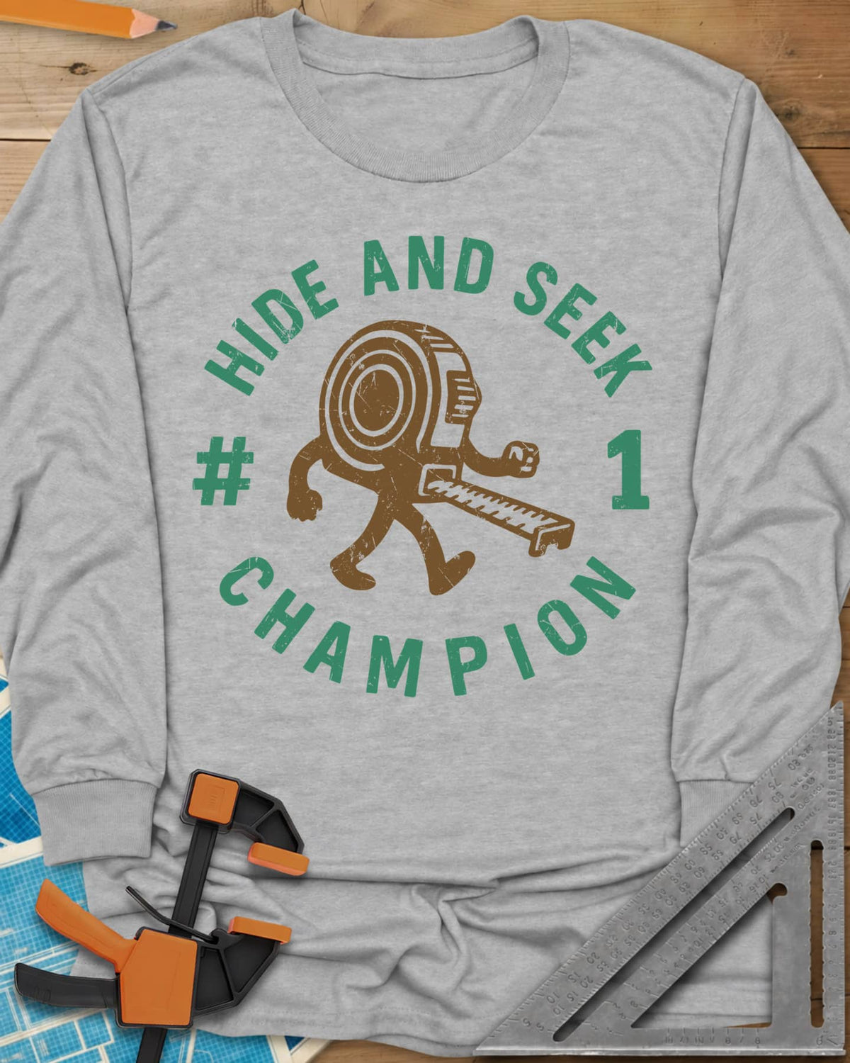 Hide And Seek long sleeve shirt in Sport Grey, a walking tape measure character inside a round badge