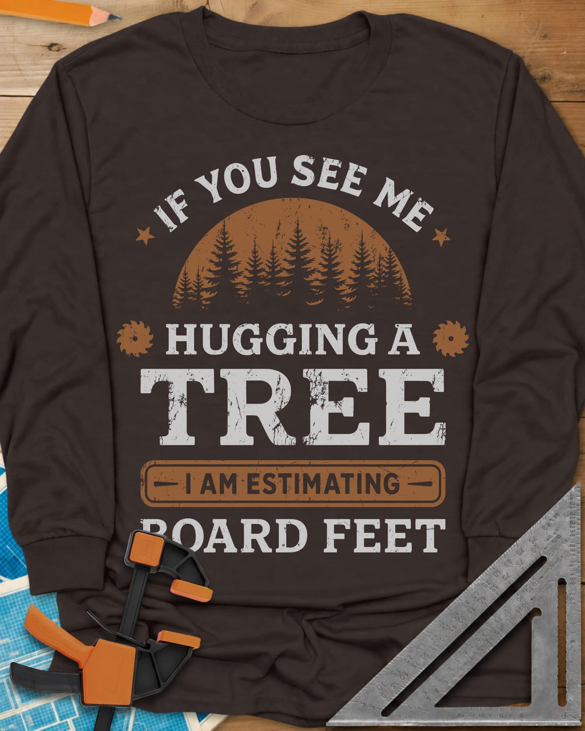 Hugging a Tree long sleeve shirt in Dark Chocolate, a pine forest at sunset with two small saw blades