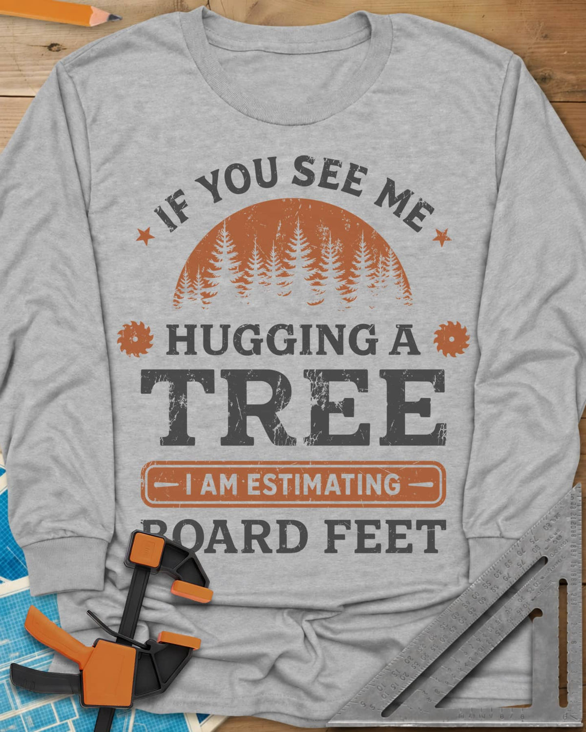 Hugging a Tree long sleeve shirt in Sport Grey, a pine forest at sunset with two small saw blades