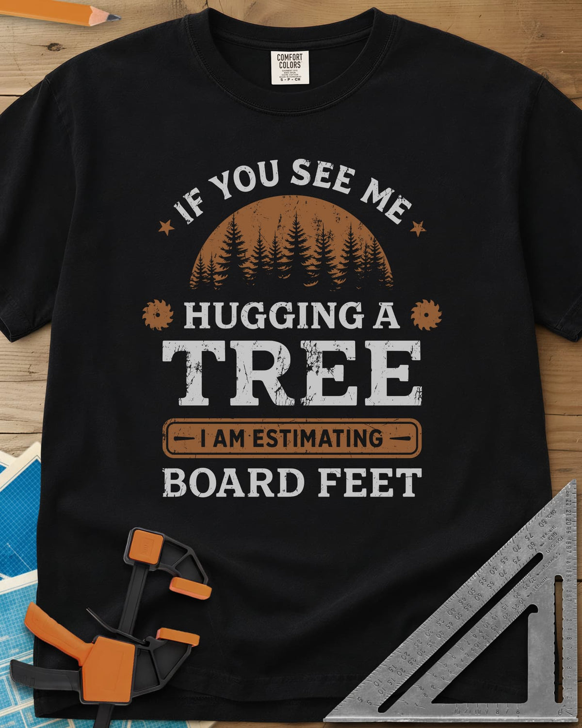 Hugging a Tree heavyweight tee in Black, a pine forest at sunset with two small saw blades