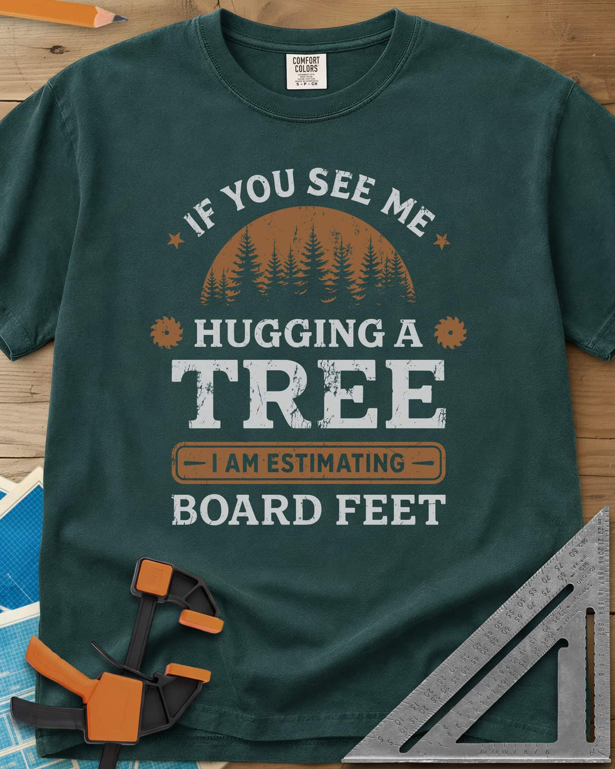 Hugging a Tree heavyweight tee in Blue Spruce, a pine forest at sunset with two small saw blades