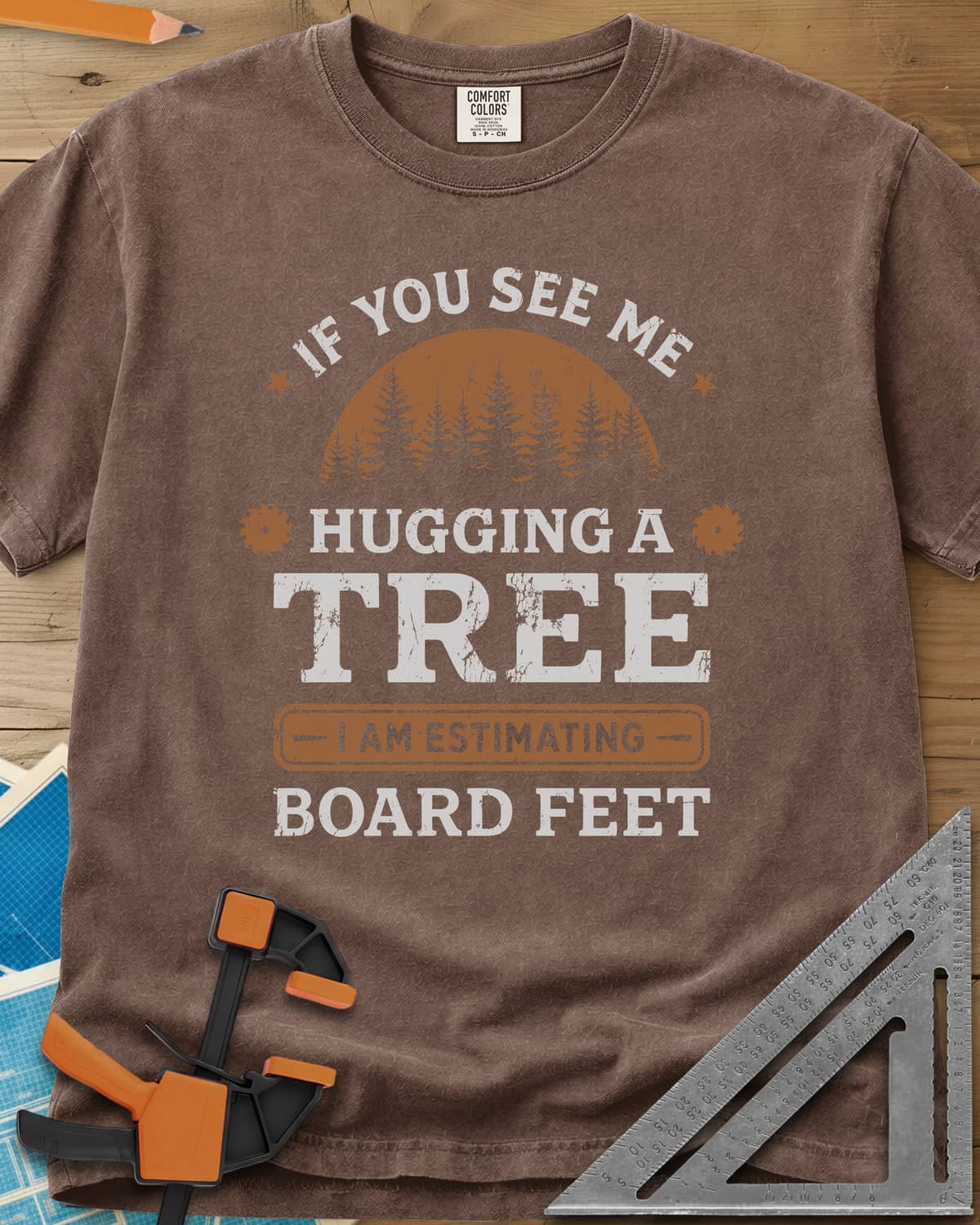 Hugging a Tree heavyweight tee in Espresso, a pine forest at sunset with two small saw blades