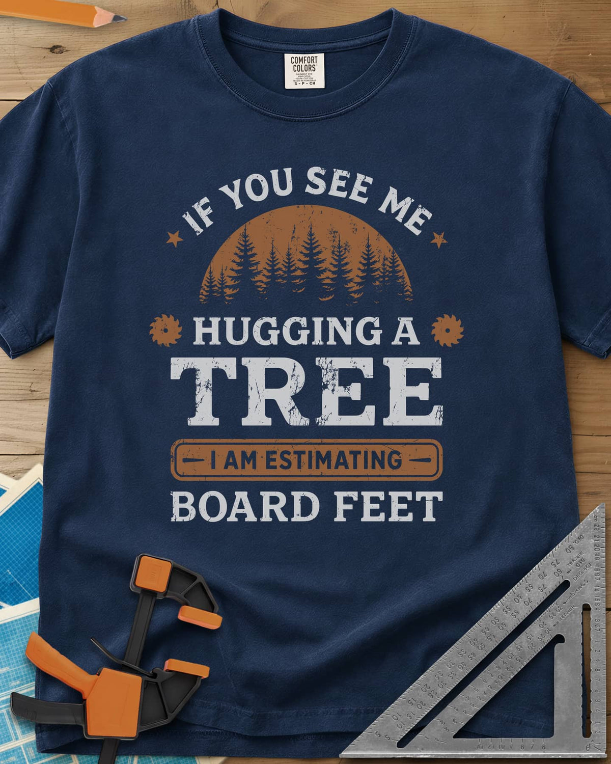 Hugging a Tree heavyweight tee in Navy, a pine forest at sunset with two small saw blades