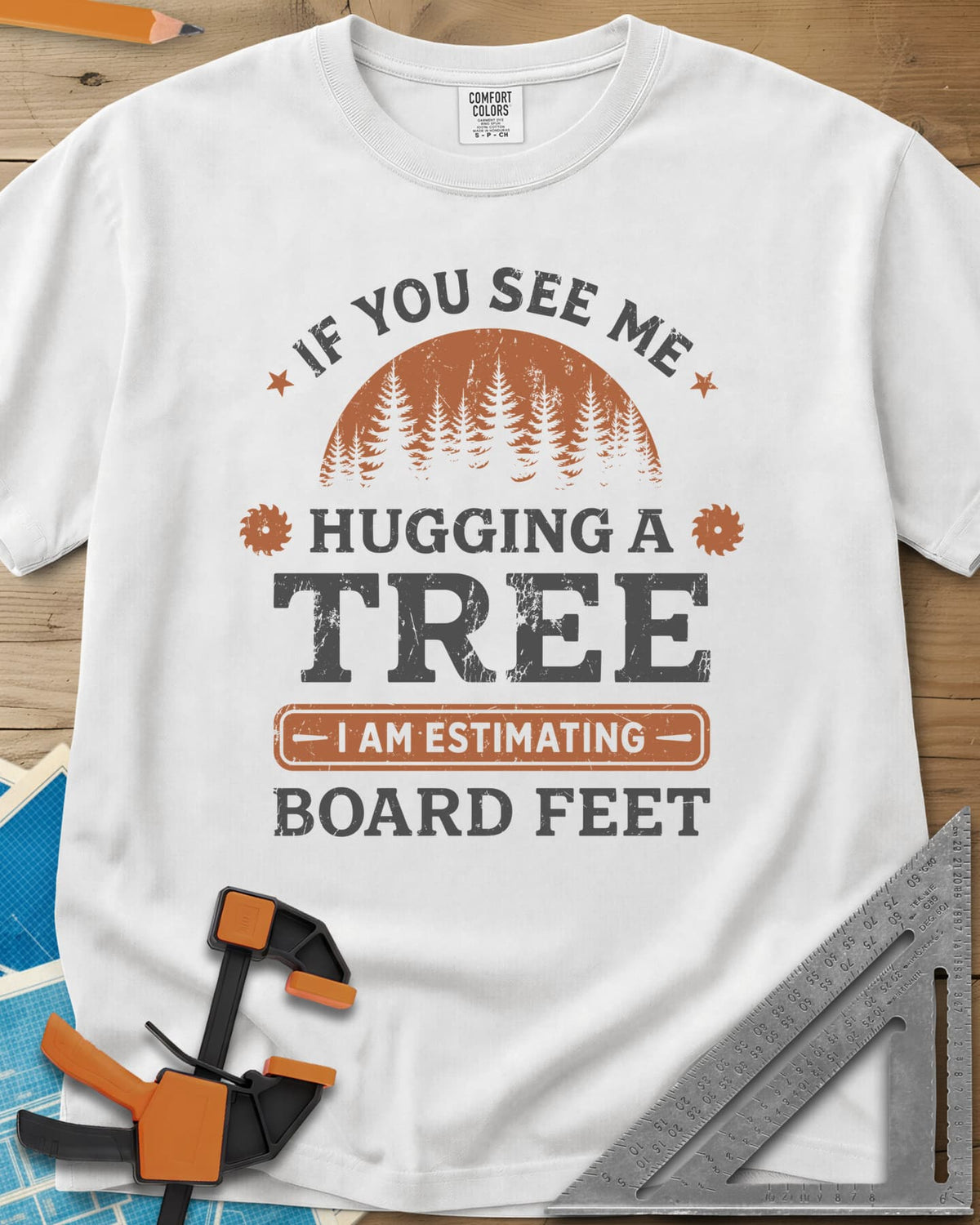 Hugging a Tree heavyweight tee in White, a pine forest at sunset with two small saw blades