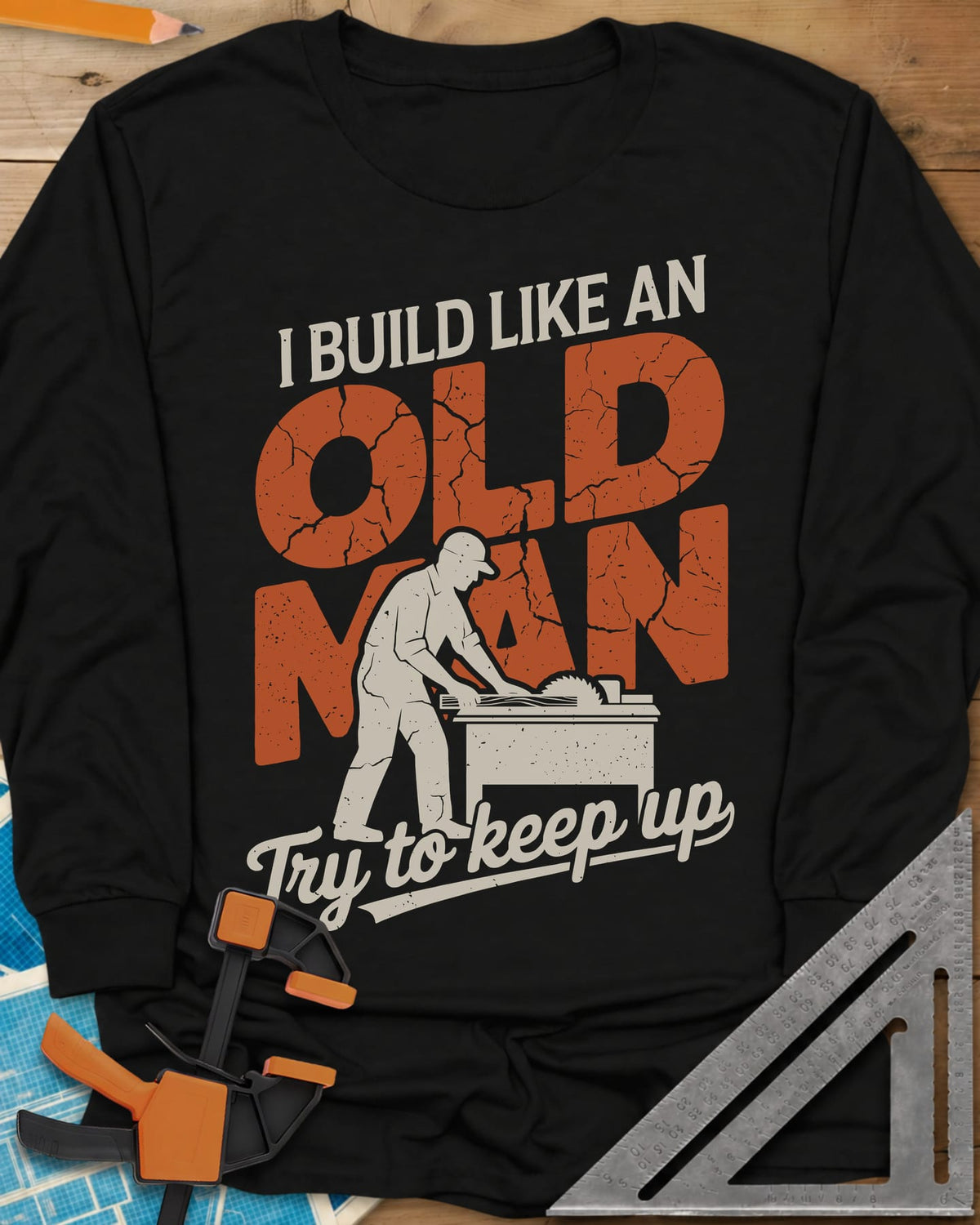 I Build Like An Old Man Woodworking long sleeve shirt in Black, a man in a cap pushing a board through a table saw