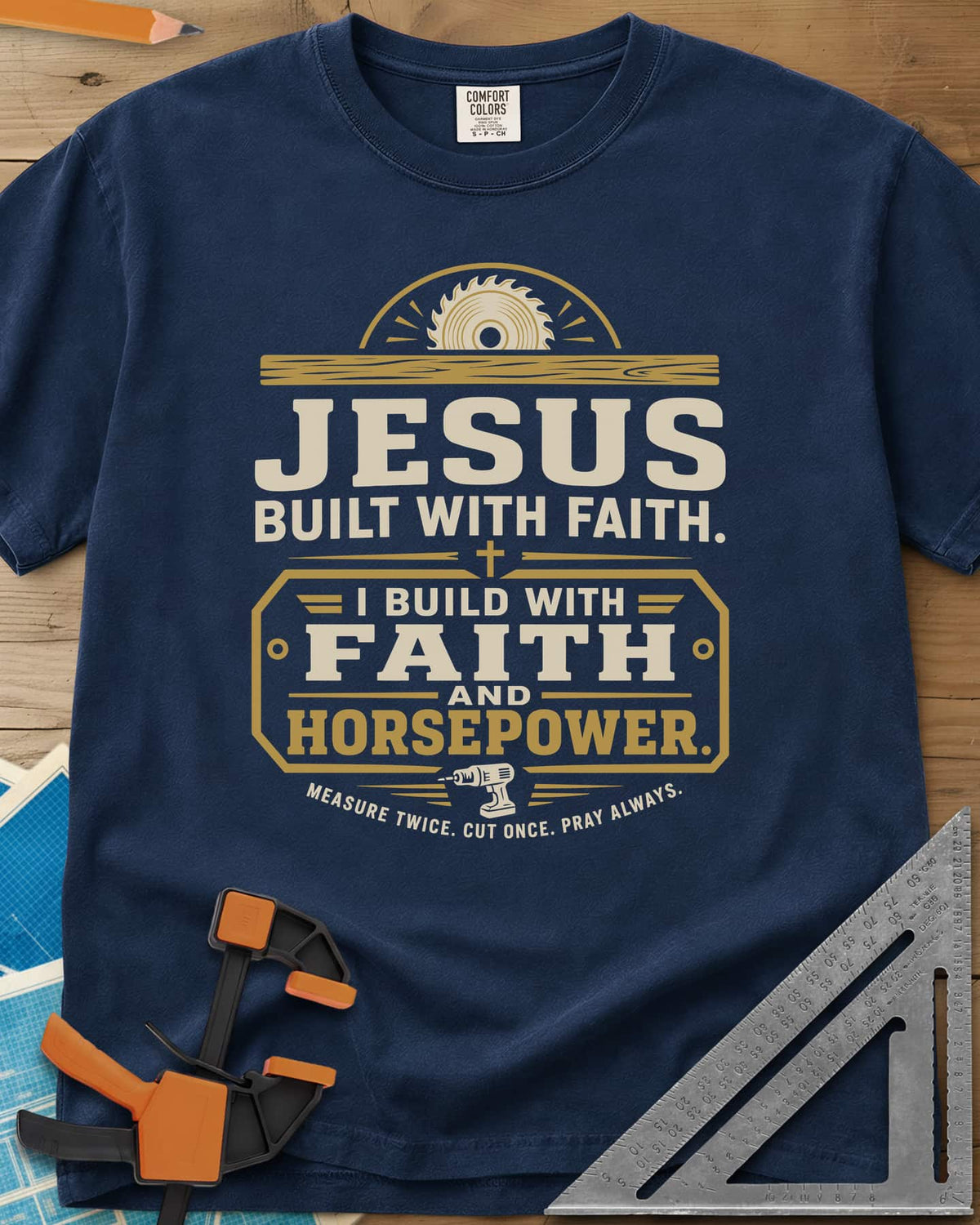 I Build With Faith And Horsepower heavyweight tee in Navy, saw blade over a plank above a plaque with a cordless drill
