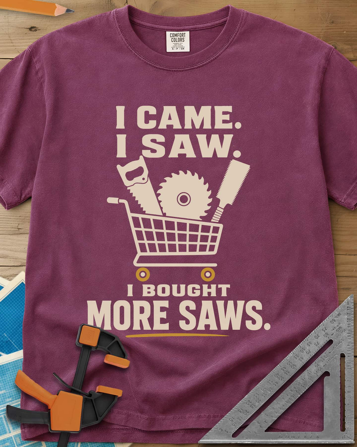 I Came I Saw I Bought More Saws heavyweight tee in Berry, a shopping cart holding a handsaw, a saw blade and a pull saw