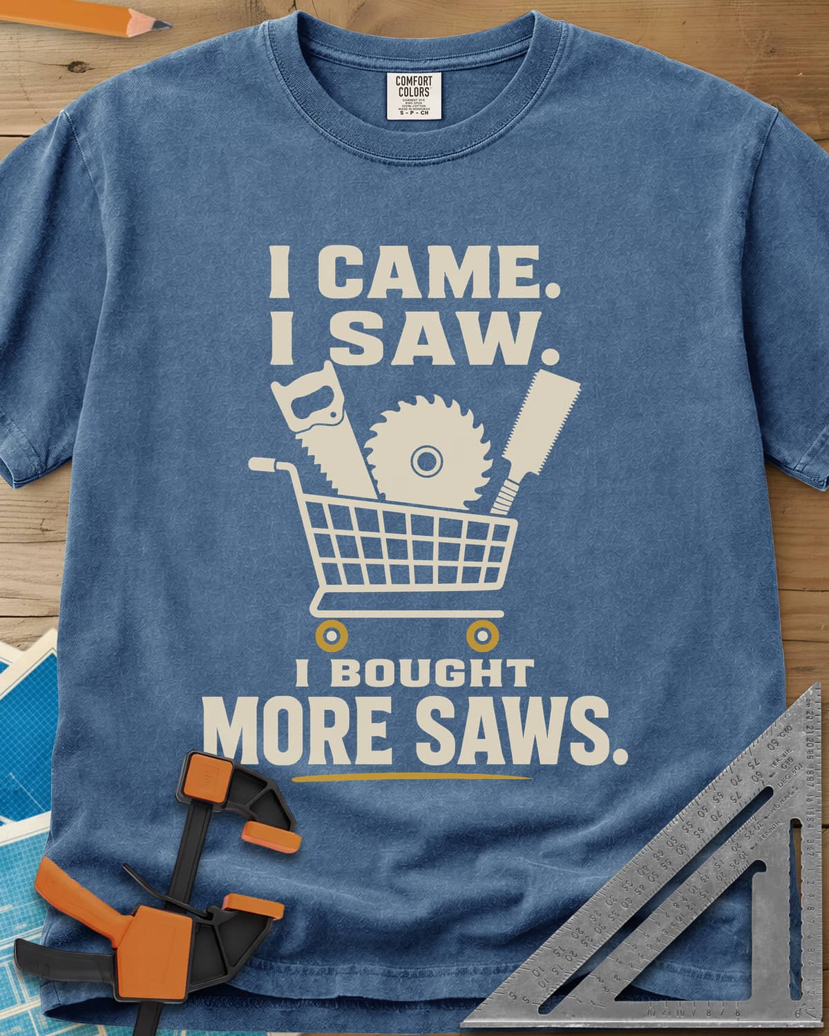 I Came I Saw I Bought More Saws heavyweight tee in Blue Jean, a shopping cart holding a handsaw, a saw blade and a pull saw