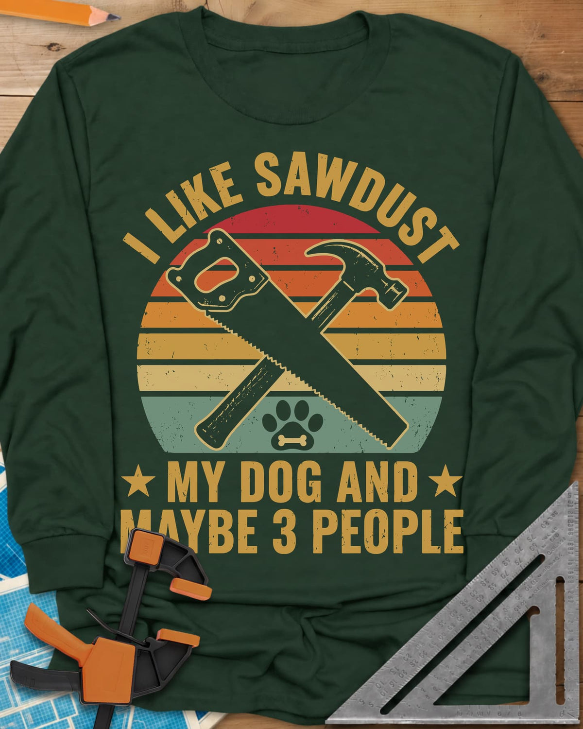I Like Sawdust long sleeve shirt in Forest Green, a hand saw crossed with a hammer over a paw print on retro stripes